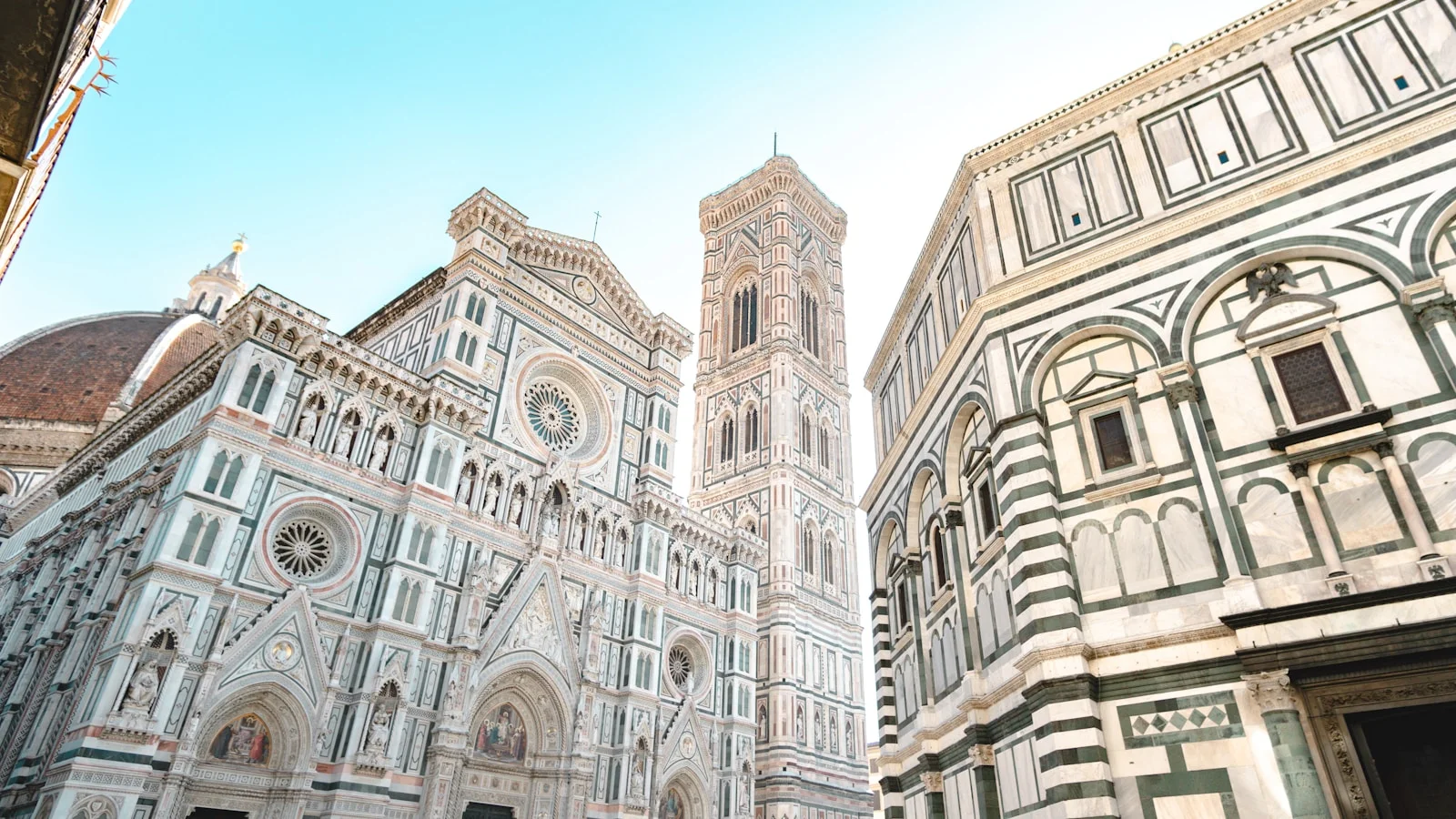 Florence skyline dominated by Brunelleschi's terracotta-tiled Duomo dome, with Giotto's bell tower beside it and Tuscan hills behind the Arno valley.